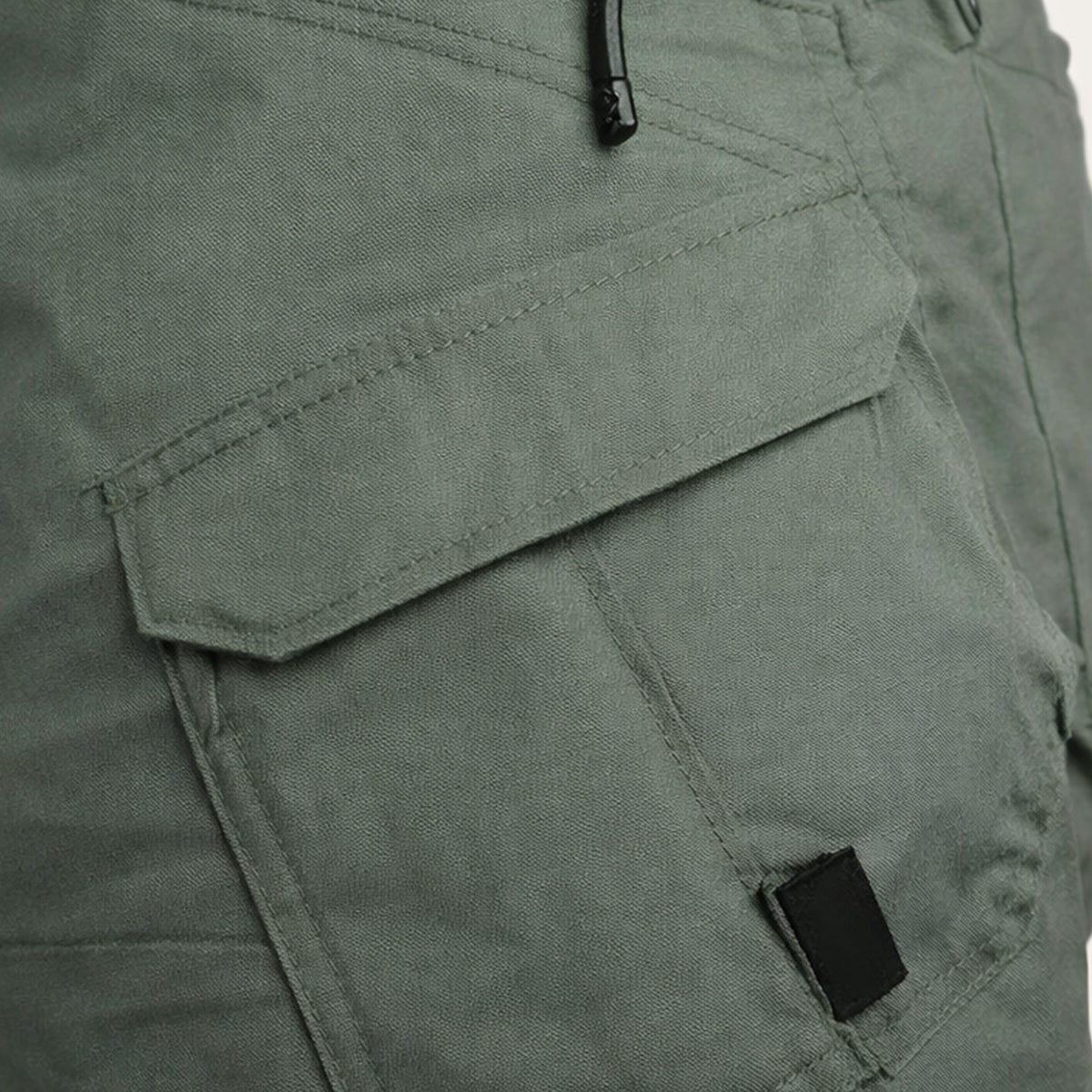 Close-up of olive cargo shorts side pocket with flap and zipper detail