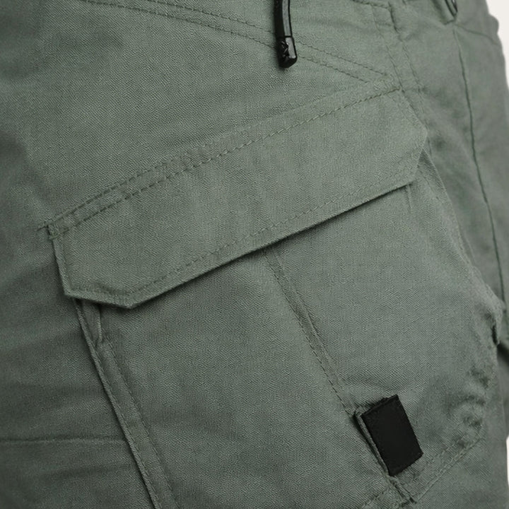Close-up of olive cargo shorts side pocket with flap and zipper detail