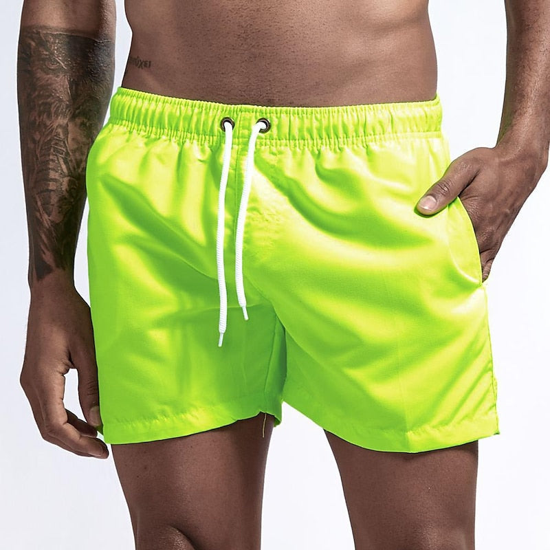 Neon yellow-green men's quick dry swim shorts with white drawstring waist and side pockets, front view