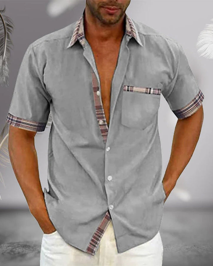 Light gray short sleeve button up shirt with collar, plaid trim, chest pocket, and relaxed fit