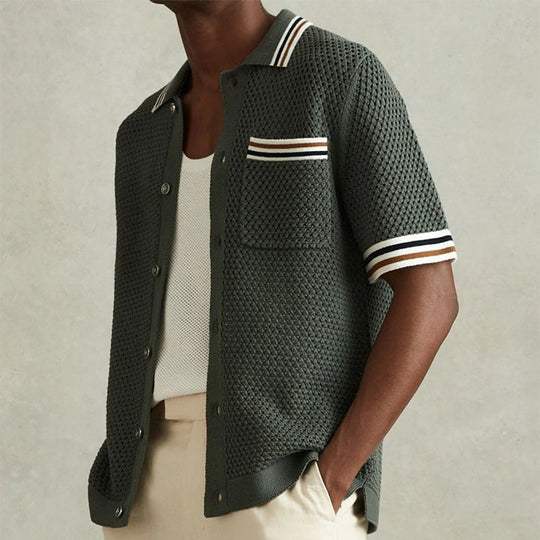 Side view of men's knit polo shirt with short sleeves, textured dark green fabric, and striped trim