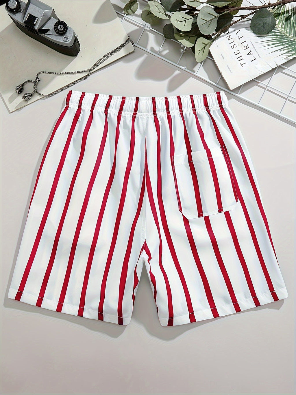 Back view of men's striped swim shorts in white and red with elastic waistband