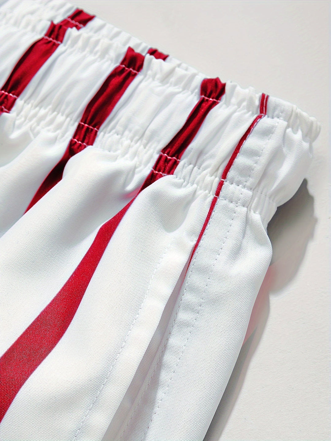 Close-up of men's swim shorts drawstring and side pocket in white with red stripes