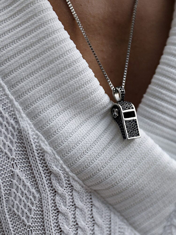Close up of white cable knit V neck top with ribbed trim and pendant necklace