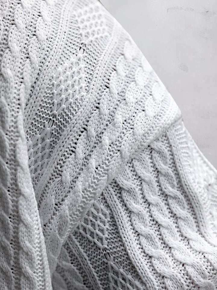 Close up of white cable knit fabric showing raised knit texture and pattern detail