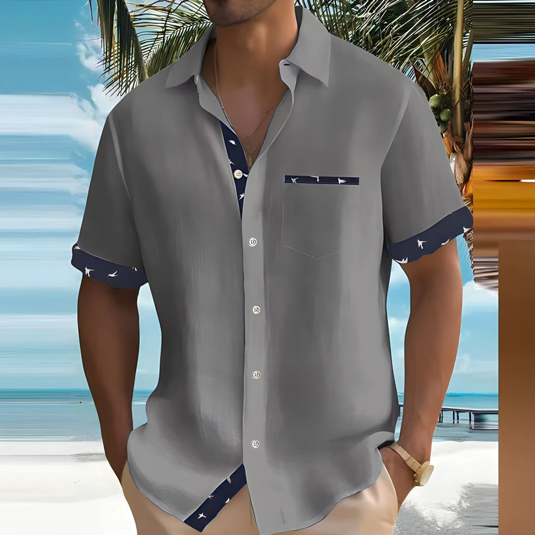 Gray men's casual button down shirt with short sleeves, navy patterned trim, and front pocket