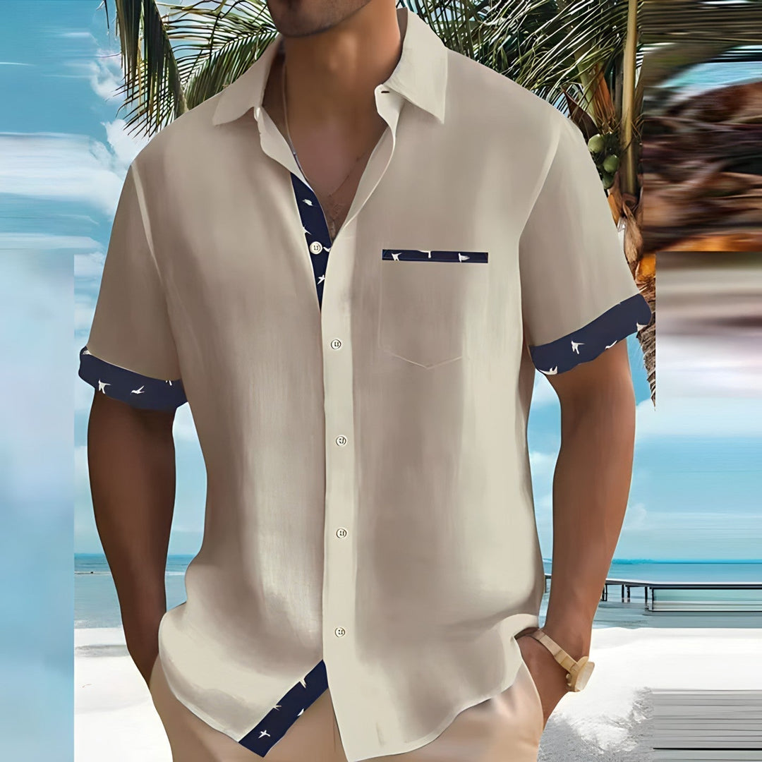 Beige men's short sleeve button down shirt with navy patterned trim and chest pocket