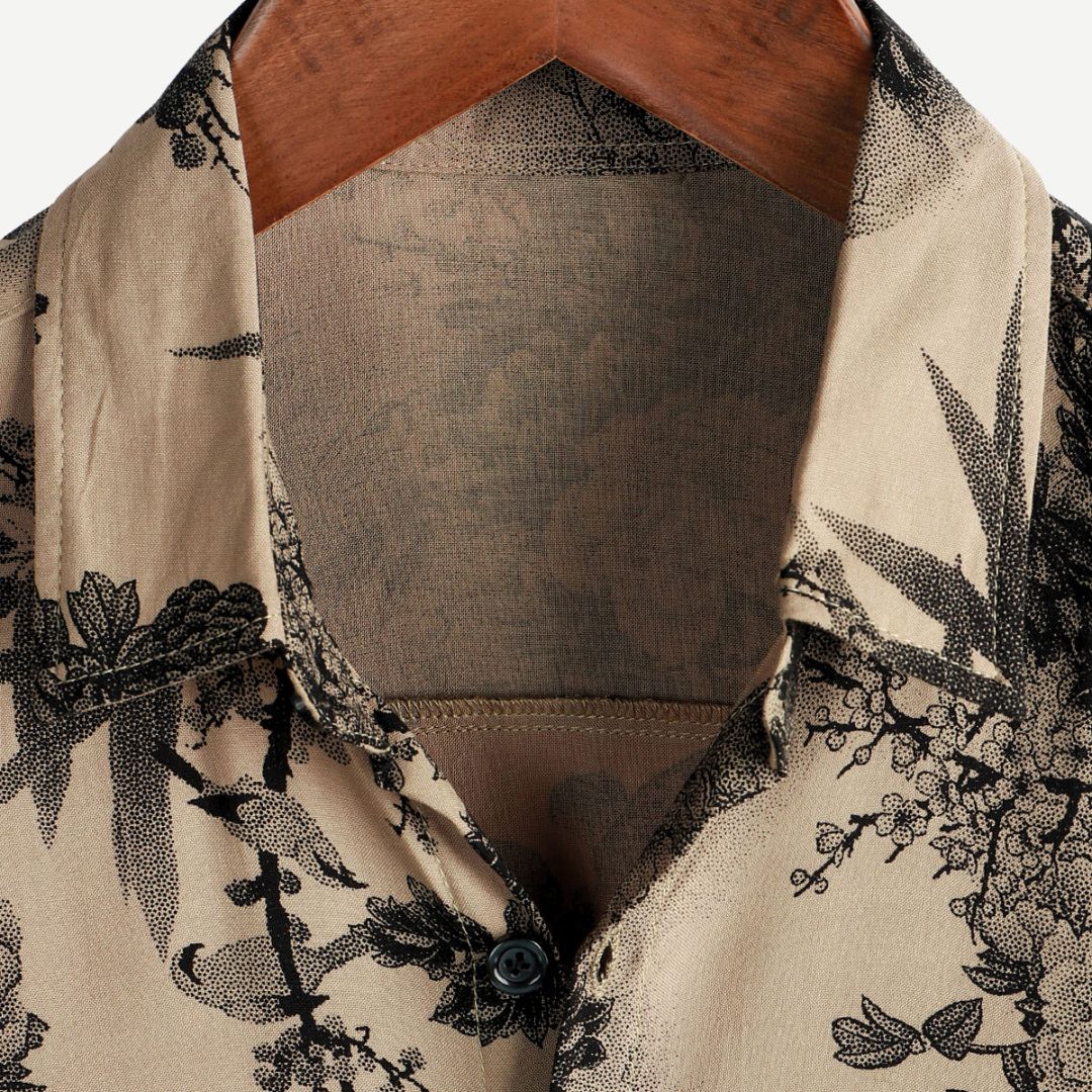 Close-up of men's floral button down shirt collar and neckline in beige with black print