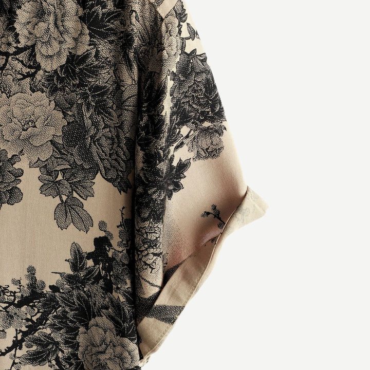 Side close-up of men's floral button down shirt sleeve and hem in beige and black