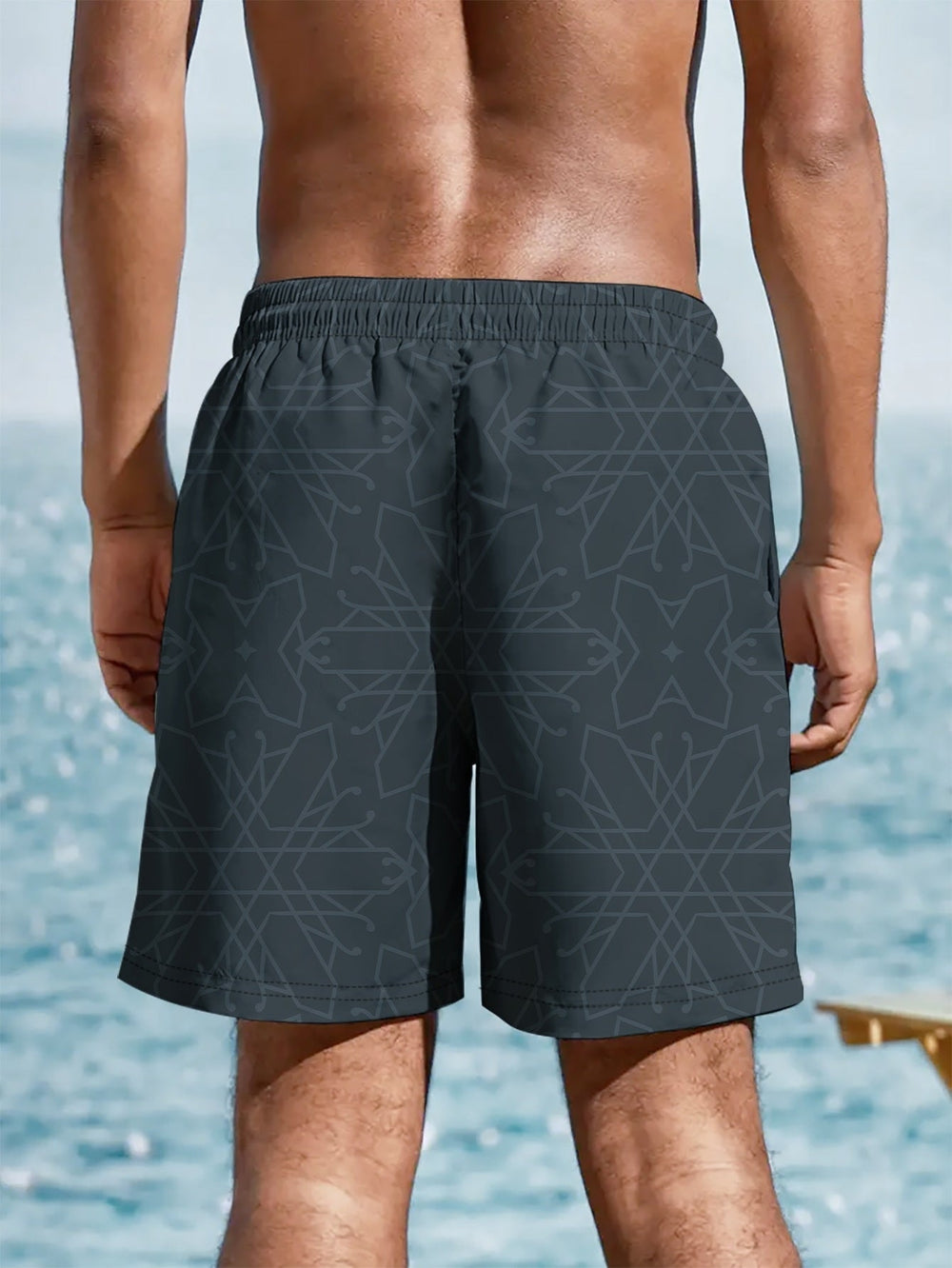 Back view of black summer swim shorts with geometric pattern and elastic waist