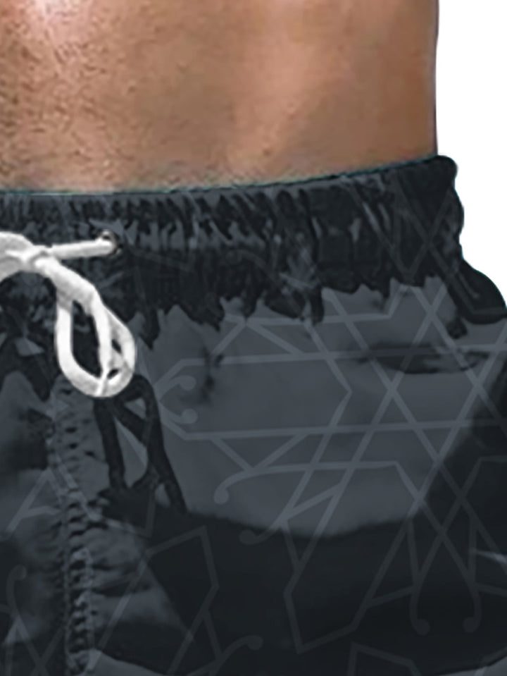 Close-up of black summer swim shorts showing geometric print and hem stitching
