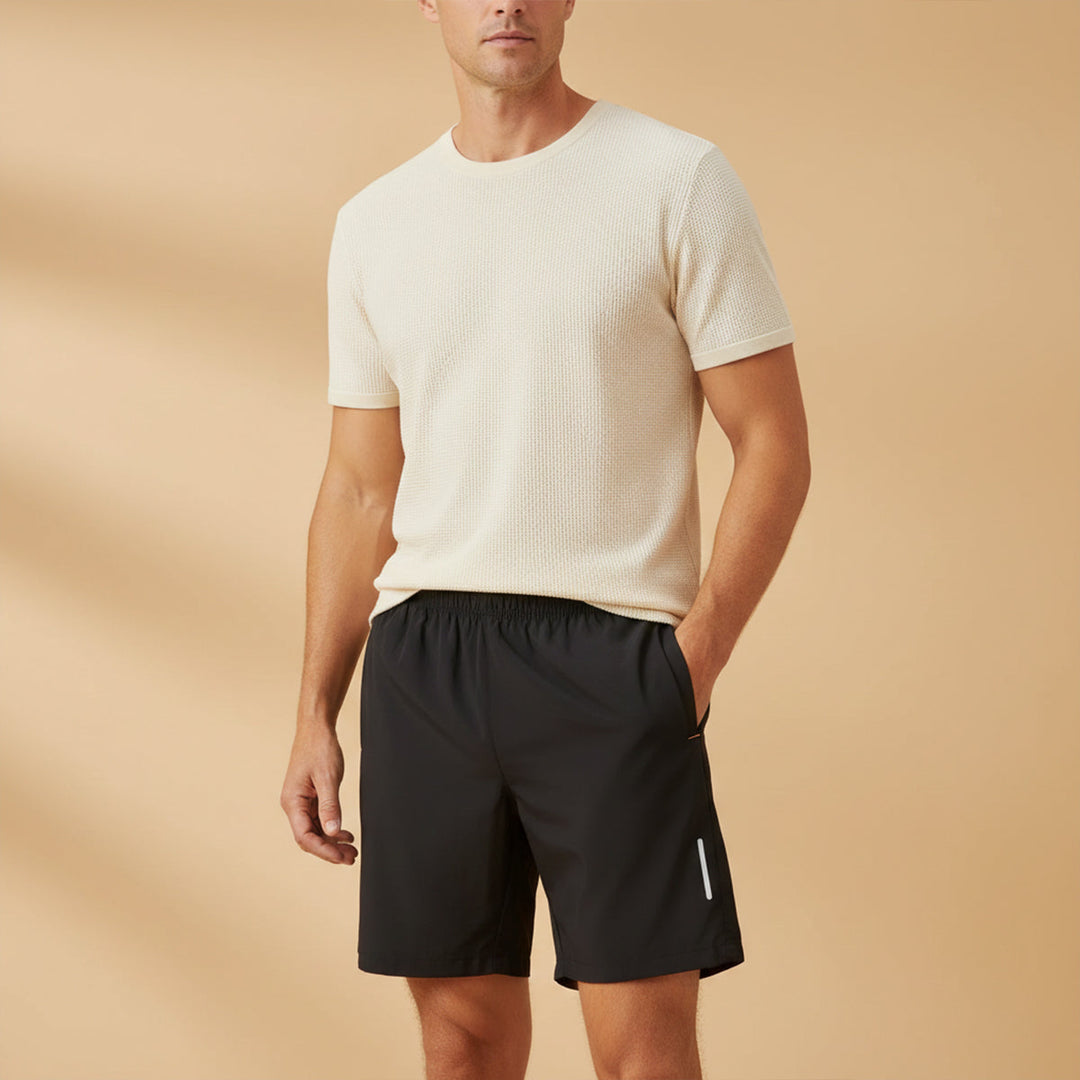 Model wearing black lightweight running shorts with pockets and reflective side accents