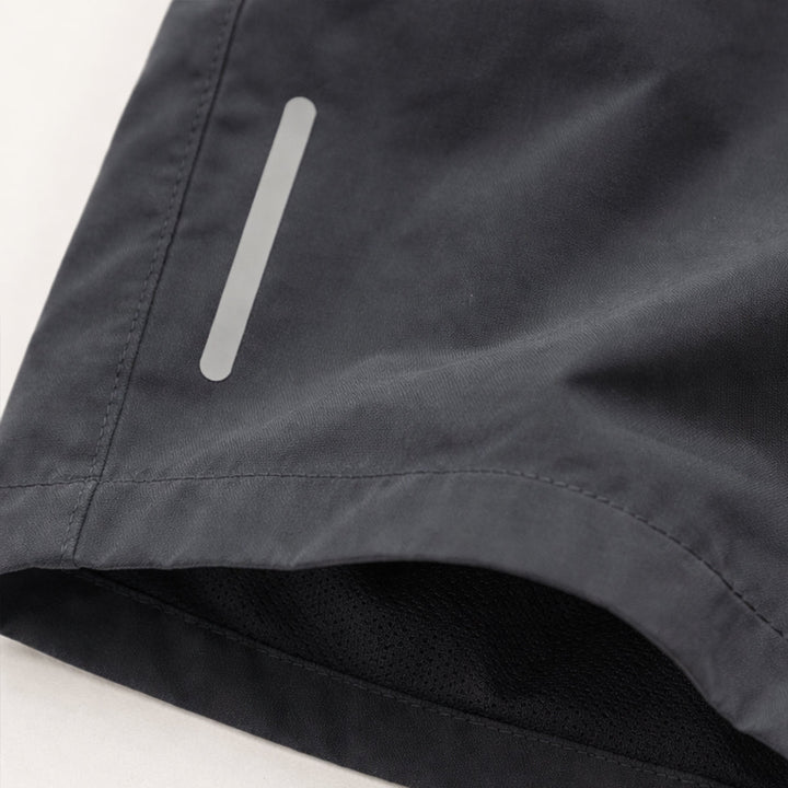 Close-up of reflective strip and hem on dark gray men's athletic shorts with pockets