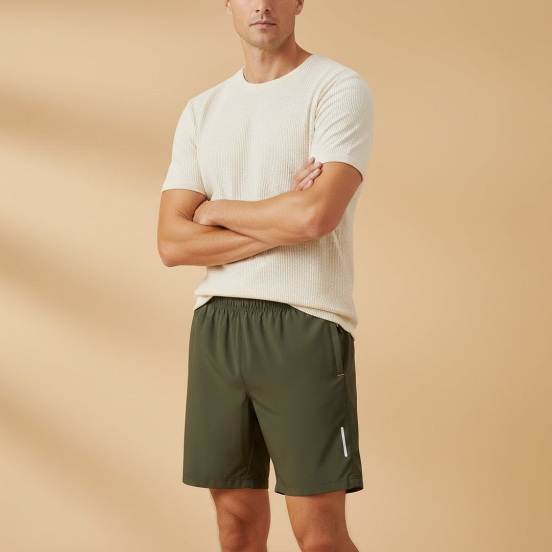 Model wearing olive green lightweight running shorts with pockets and reflective accents
