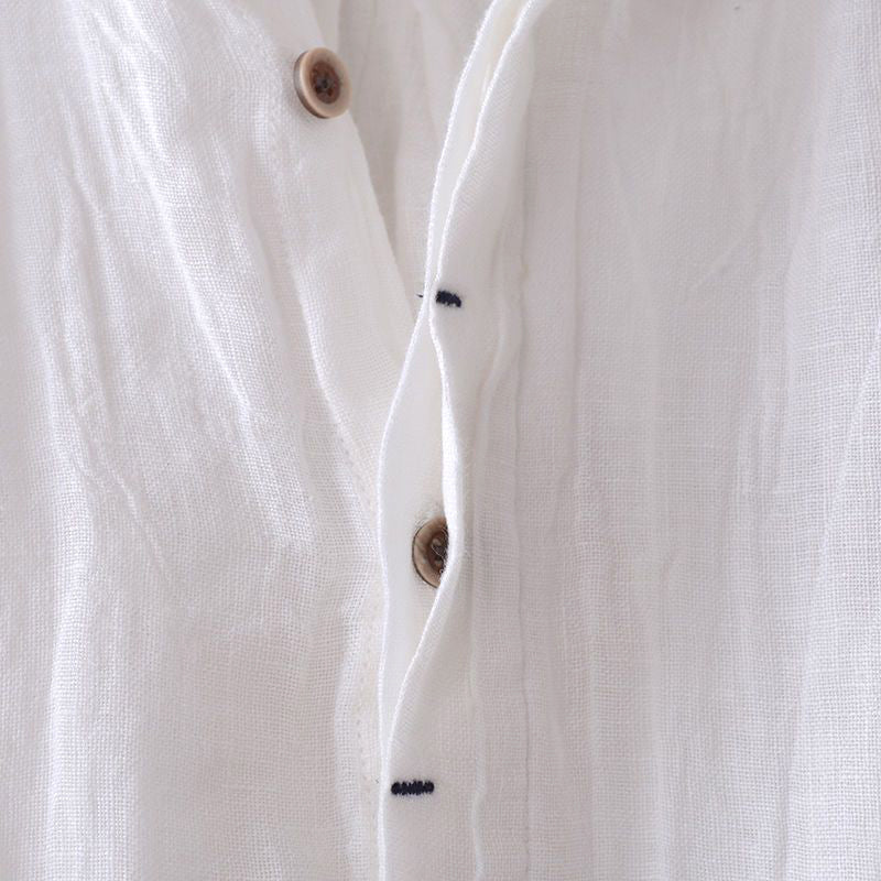 Close-up of white men's linen shirt button placket with natural texture and brown buttons