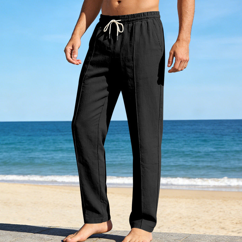 Black men's summer linen pants with straight leg cut and drawstring waist on beach