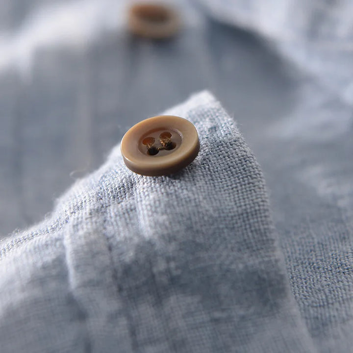 Macro view of shirt button and linen weave on a light blue summer shirt