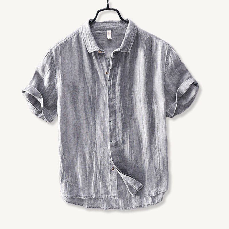 Close-up of tan button on light blue men's linen shirt with soft fabric texture