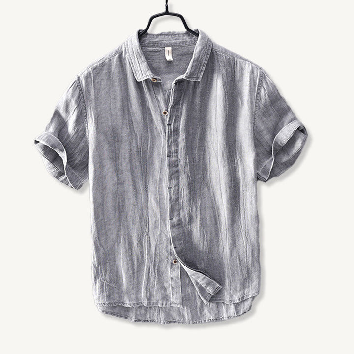 Close-up of tan button on light blue men's linen shirt with soft fabric texture