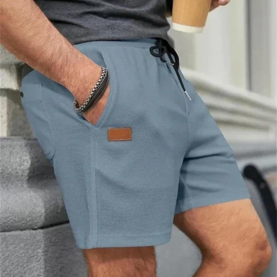 Blue linen shorts for men worn at the side, drawstring waist and relaxed summer fit