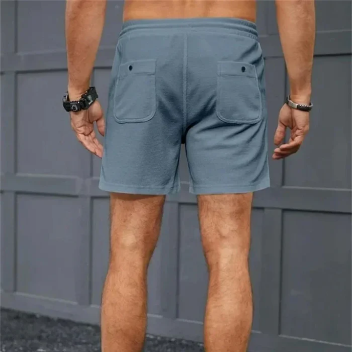 Back view of blue men's linen shorts with drawstring, rear patch pockets and casual fit