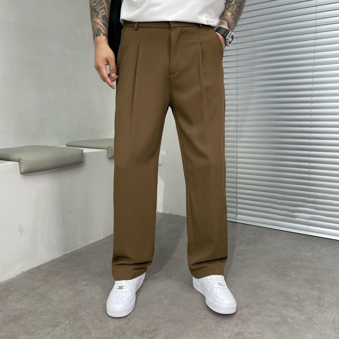 Brown pleated straight leg linen pants shown with a white tee and casual white sneakers