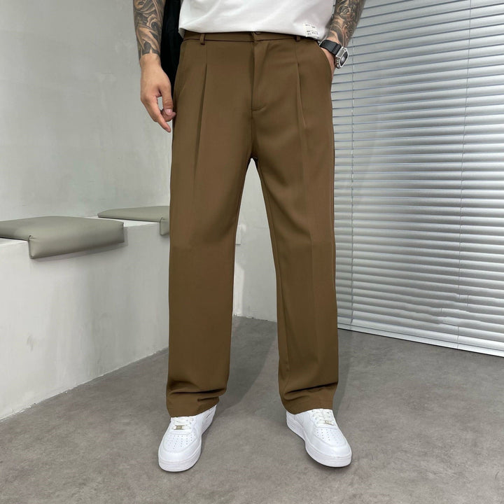 Brown pleated straight leg linen pants shown with a white tee and casual white sneakers