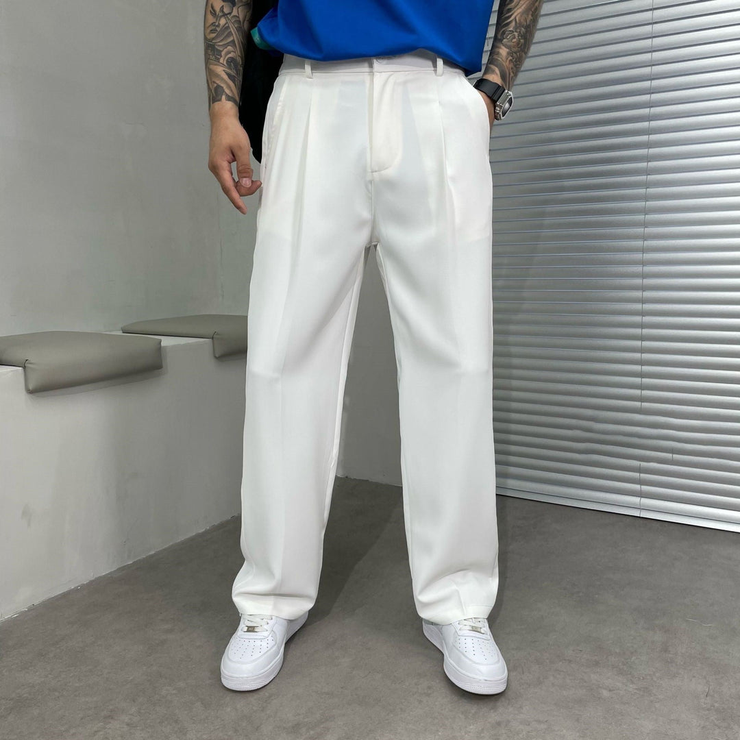 White pleated straight leg linen pants paired with a bright blue shirt and white sneakers