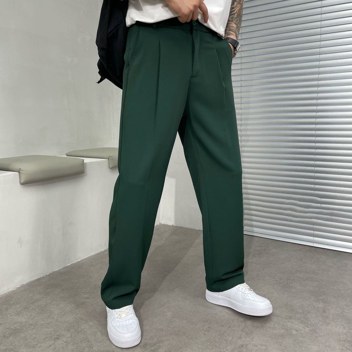 Dark green pleated straight leg linen pants shown at an angle with a relaxed summer suit look