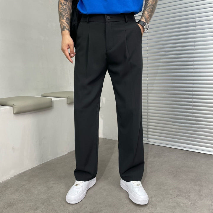 Black pleated straight leg linen pants styled with white sneakers and a tucked blue shirt