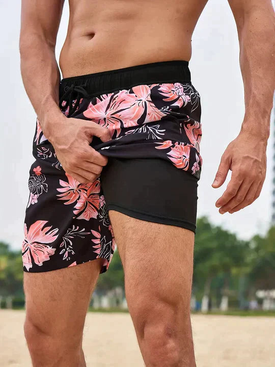 Black floral men's swim shorts with pink hibiscus print showing built-in black liner shorts