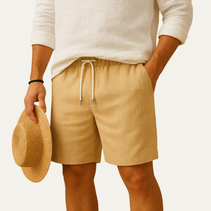 Beige striped men's drawstring shorts styled with a white top and straw hat