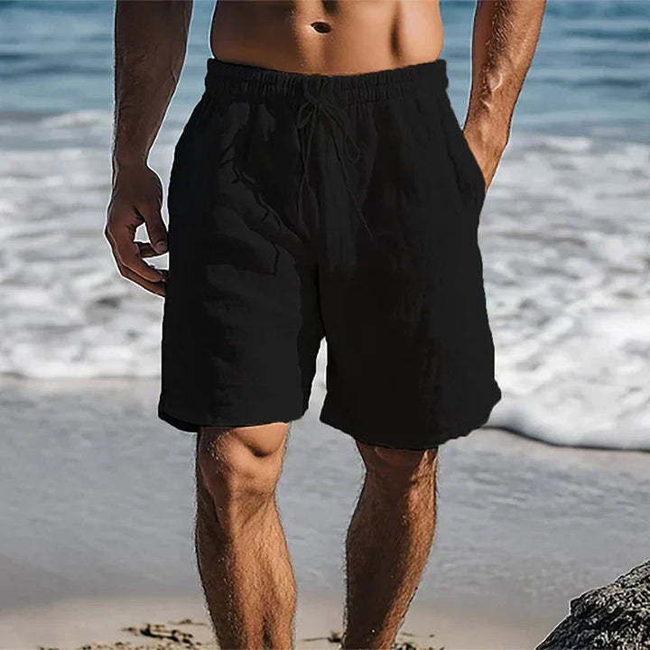 Black men's summer swim shorts with pockets and elastic waist on a beach
