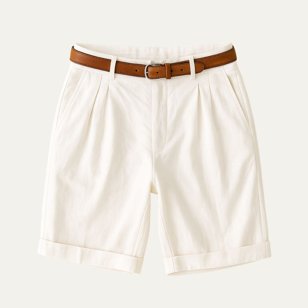 Cream tailored linen shorts with front pleats, rolled cuffs, and brown belt