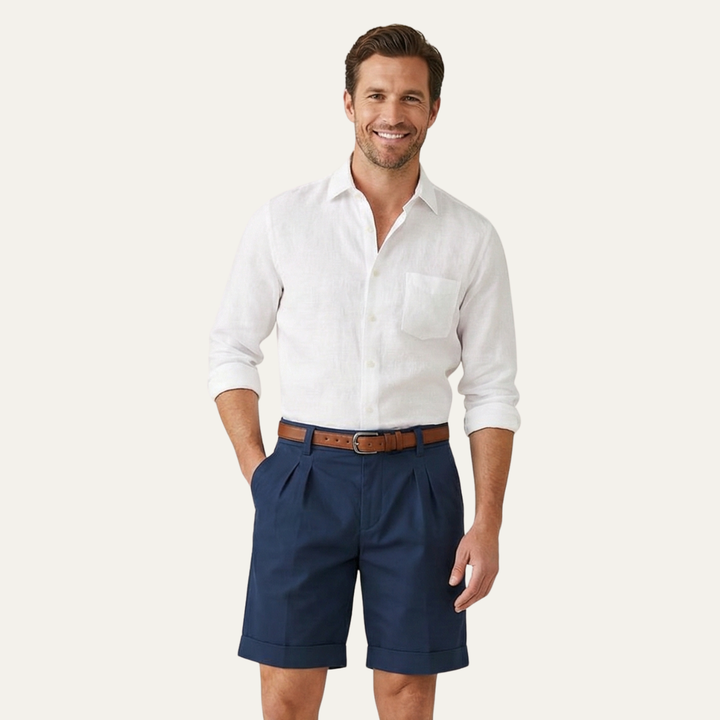Model in navy men's linen shorts with white button-up shirt and belt