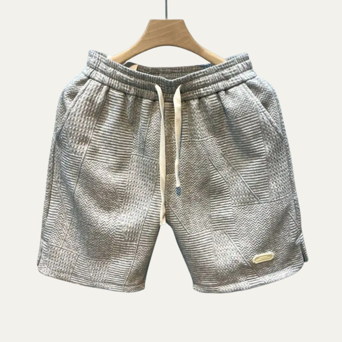 Gray textured men's summer shorts on hanger with drawstring waist and patch details