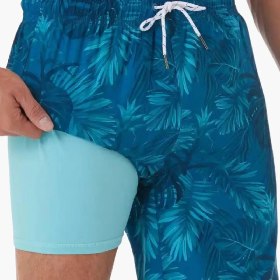 Blue tropical print swim shorts for men with leaf pattern, drawstring waist, and mesh lining
