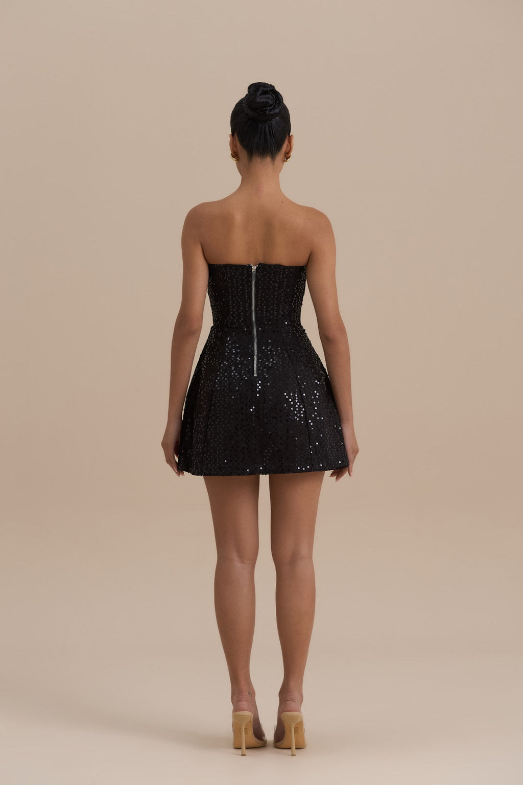 Back view black strapless sequin mini dress showing center zipper and flared skirt silhouette