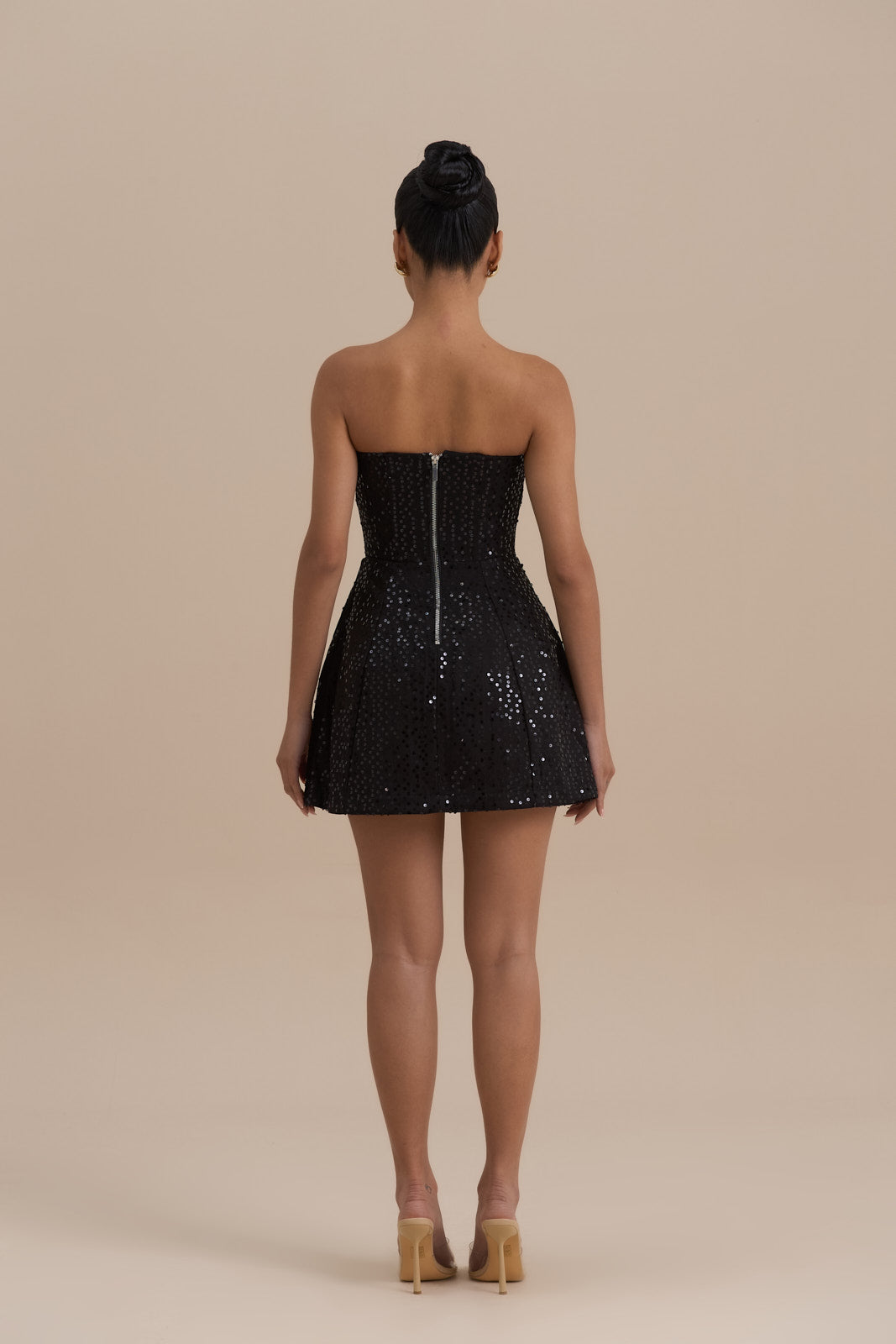 Back view black strapless sequin mini dress showing center zipper and flared skirt silhouette