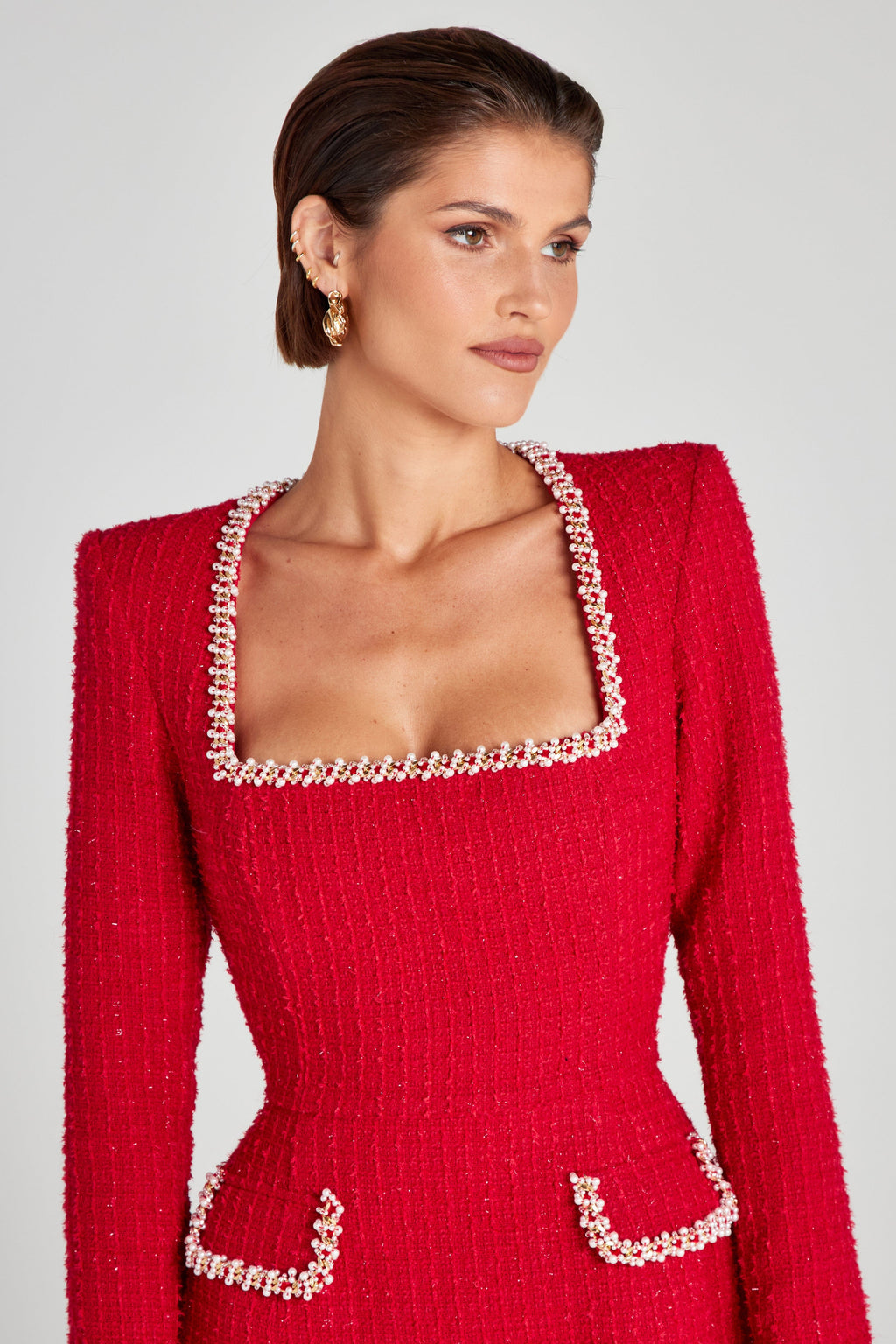 Close-up of red square neck mini dress showing pearl beaded neckline trim and textured fabric