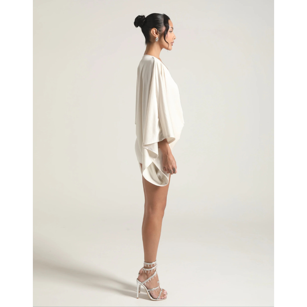 Side view of ivory V neck mini dress with flowing cape sleeves and short hem