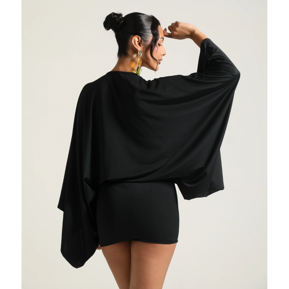 Back view of black mini dress with cape style sleeves and short fitted hem