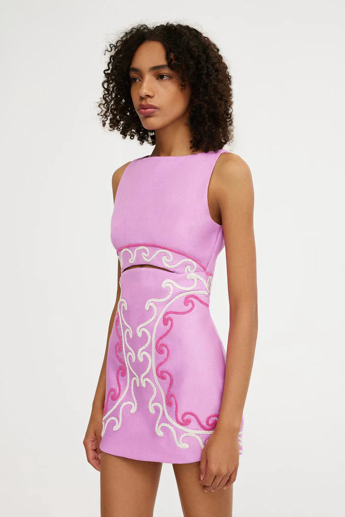 Side view of pink embroidered mini dress with sleeveless cutout bodice and fitted skirt