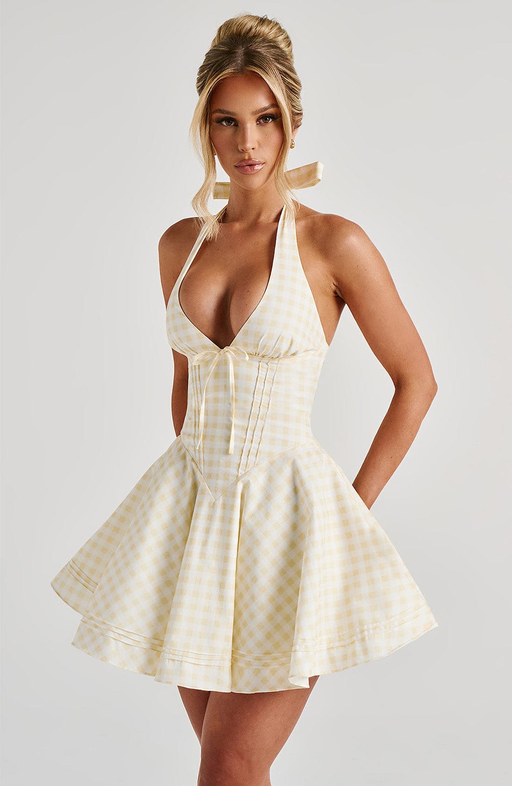 Three-quarter view yellow gingham halter mini dress with deep V neckline, corset waist, full skirt
