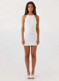 Front view of white halter mini dress with ruched texture and floral sandals