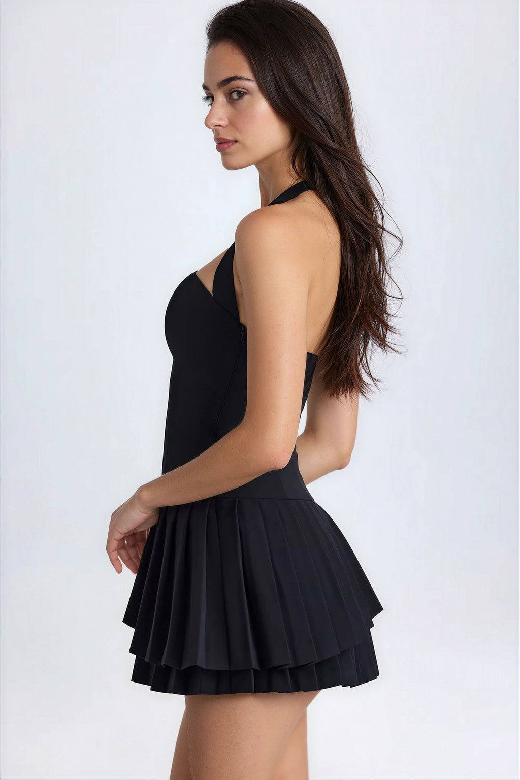 Side view of black halterneck pleated mini dress with open back detail