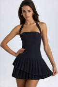 Black halterneck mini dress with pleated layered skirt and fitted bodice