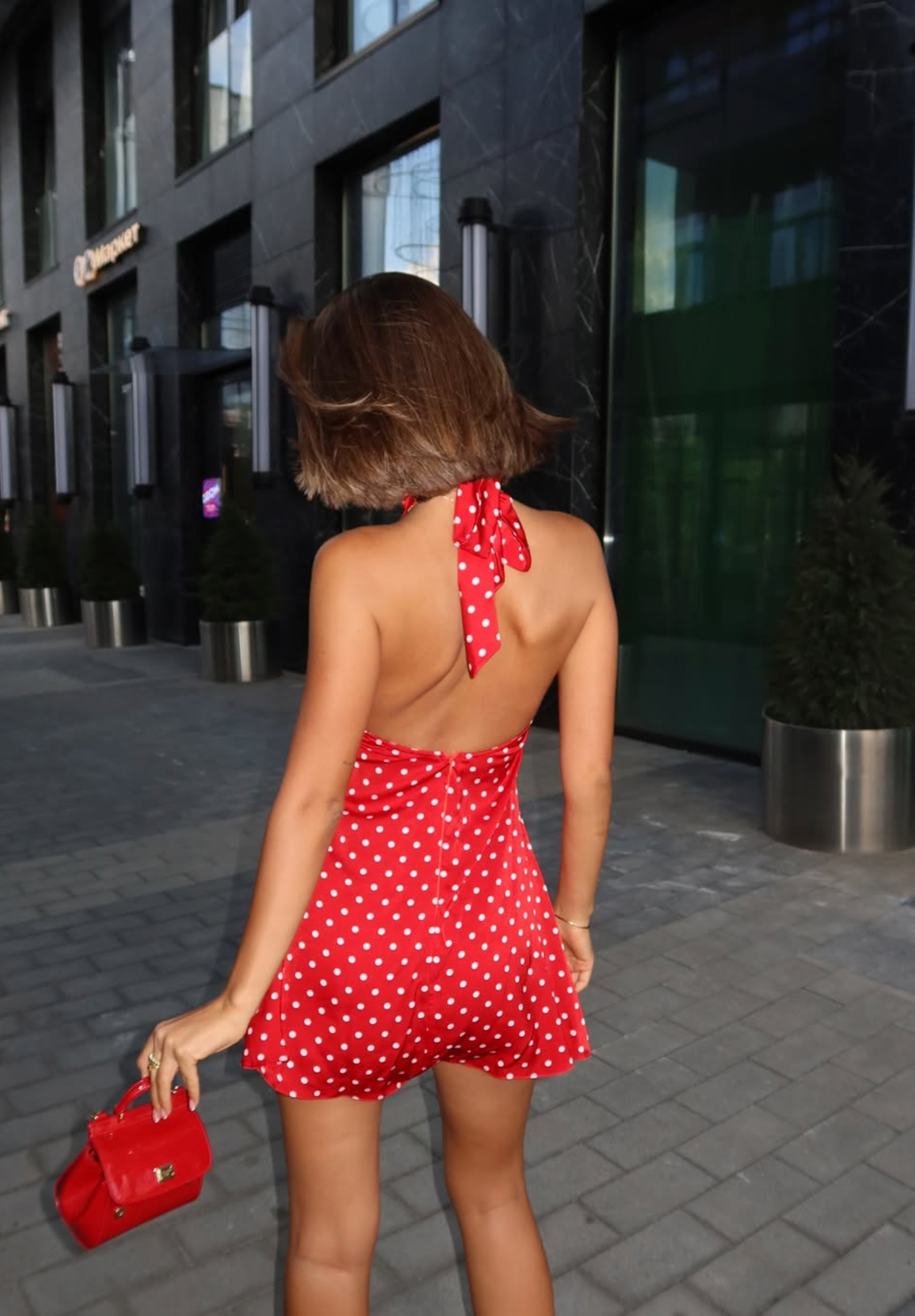 Red polka dot halter mini dress with fitted silhouette and small red handbag