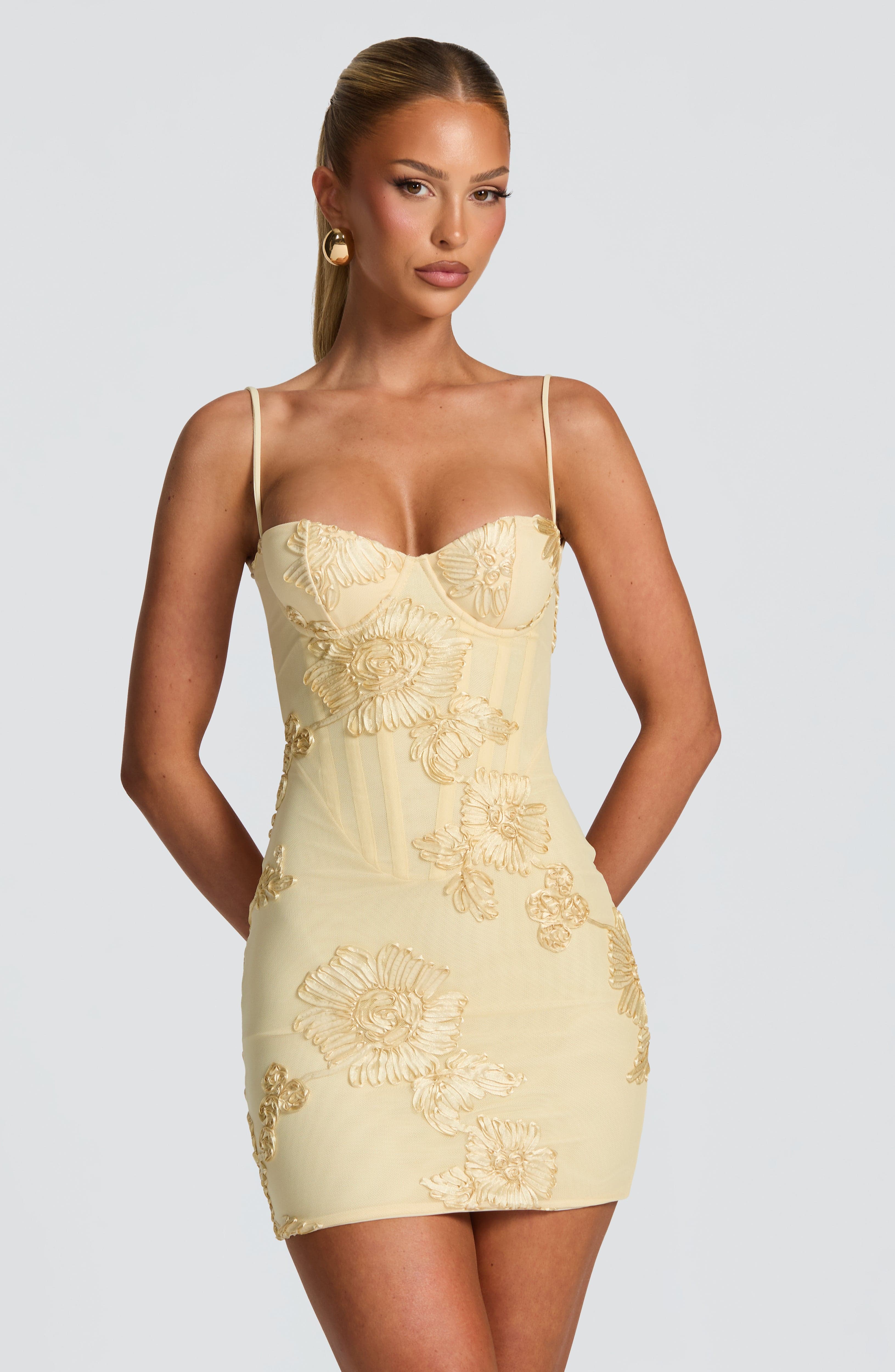 Front view of pale yellow floral corset mini dress with thin straps and fitted silhouette