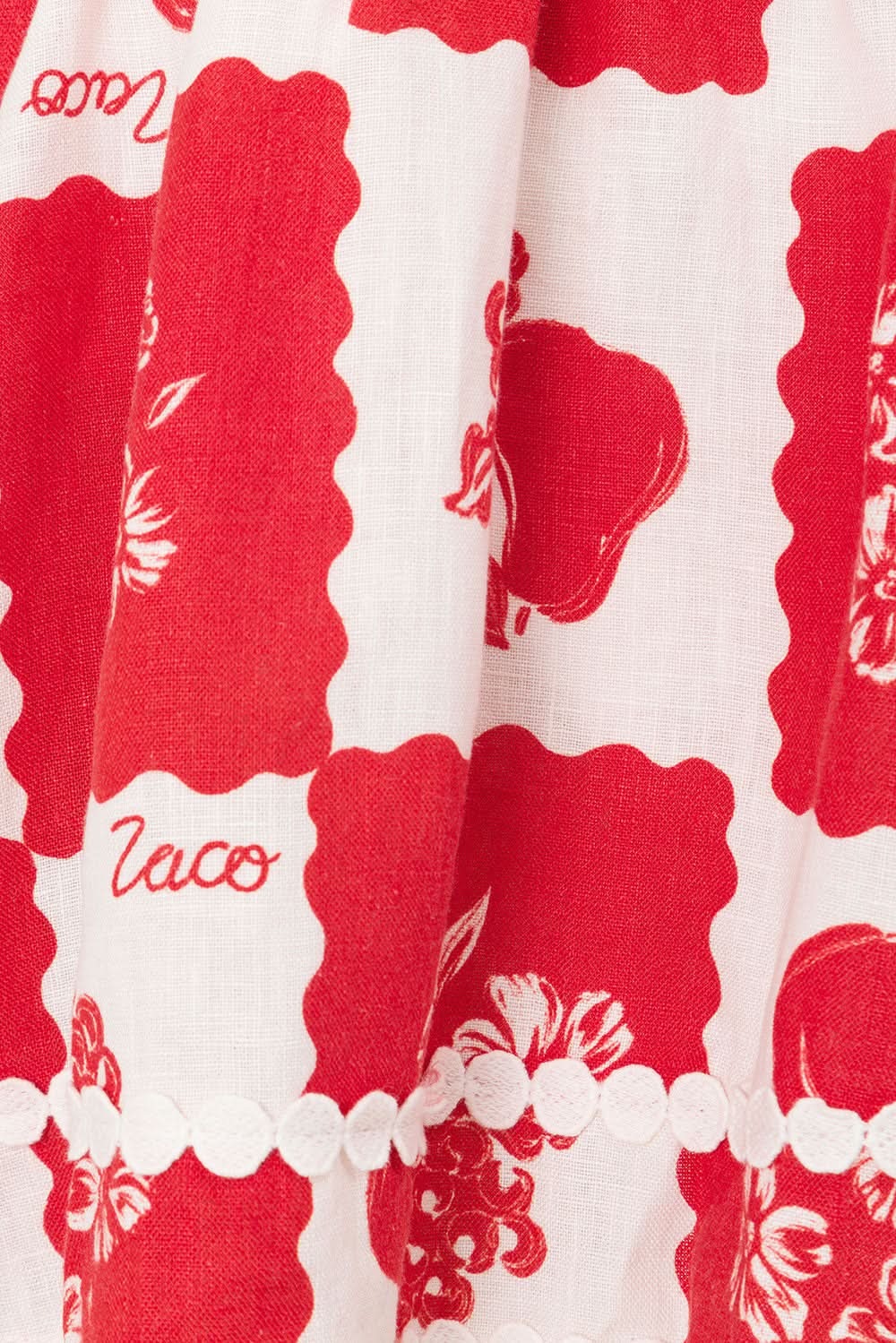 Fabric close-up of red floral print and scalloped trim on wedding guest mini dress skirt